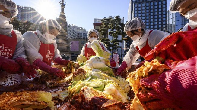 Para peserta menyiapkan kimchi, hidangan tradisional Korea dari kubis dan lobak pedas yang difermentasi, selama festival pembuatan kimchi di kuil Buddha Jogyesa, Seoul, Korea Selatan, pada (2/12/2021). [ANTHONY WALLACE / AFP]