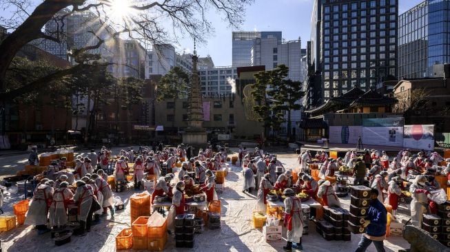 Para peserta menyiapkan kimchi, hidangan tradisional Korea dari kubis dan lobak pedas yang difermentasi, selama festival pembuatan kimchi di kuil Buddha Jogyesa, Seoul, Korea Selatan, pada (2/12/2021). [ANTHONY WALLACE / AFP]