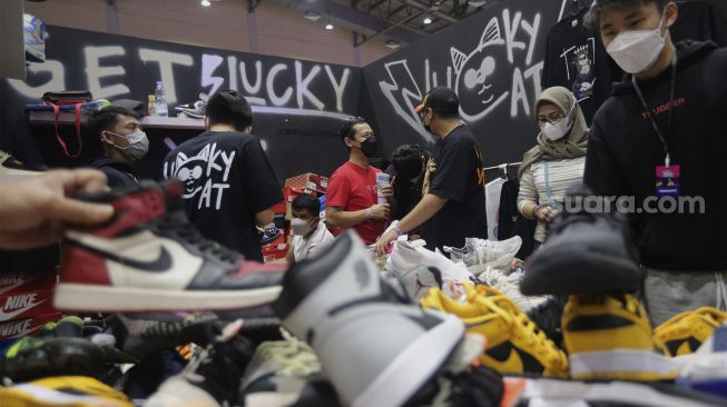 Pengunjung memilih produk yang ditawarkan pada acara Urban Sneaker Society 2021 di Jakarta Convention Center, Senayan, Jakarta, Minggu (5/12/2021). [Suara.com/Angga Budhiyanto]