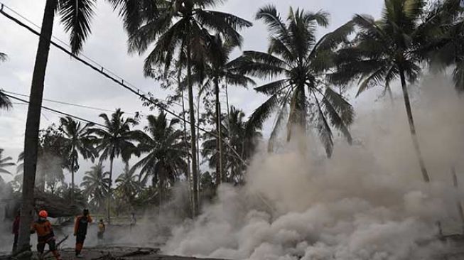 Relawan mengamati kepulan asap yang berasal dari material guguran awan panas Gunung Semeru di Desa Sumberwuluh, Lumajang, Jawa Timur, Minggu (5/12/2021). [Antara/Zabur Karuru]