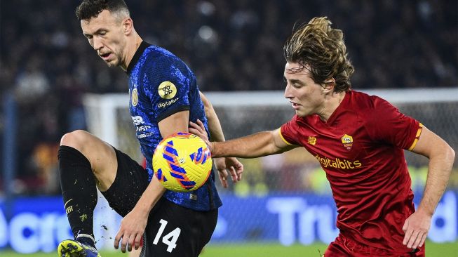 Gelandang Inter Milan Ivan Perisic (kiri) dan gelandang Roma Edoardo Bove berebut bola selama pertandingan sepak bola Serie A Italia antara AS Roma dan Inter di stadion Olimpiade, Roma, pada (4/12/2021). [VINCENZO PINTO / AFP]