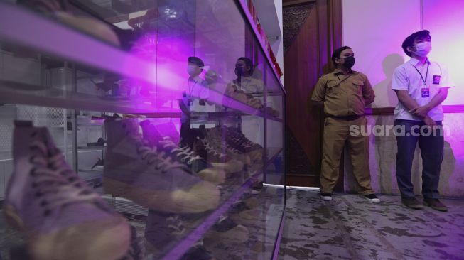 Penjaga berdiri di depan 'booth' sepatu pada acara Urban Sneaker Society 2021 di Jakarta Convention Center, Senayan, Jakarta, Minggu (5/12/2021). [Suara.com/Angga Budhiyanto]