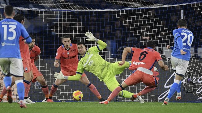 Gelandang Napoli Piotr Zielinski (kanan) mencetak gol penyeimbang melewati kiper Atalanta Juan Musso (tengah) selama pertandingan sepak bola Serie A Italia antara Napoli dan Atalanta di stadion Diego-Maradona, Naples, pada (4/12/2021). [FILIPPO MONTEFORTE / AFP]