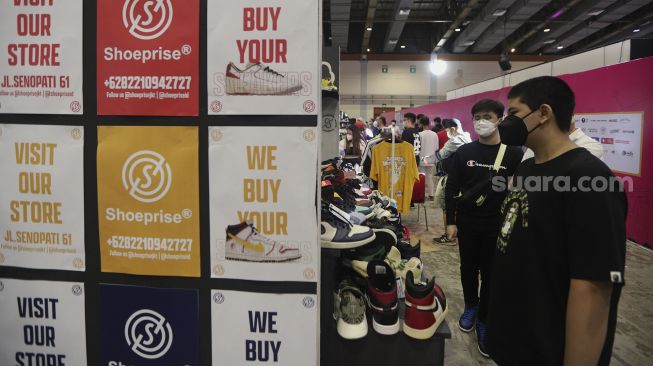 Pengunjung mengamati produk yang ditawarkan pada acara Urban Sneaker Society 2021 di Jakarta Convention Center, Senayan, Jakarta, Minggu (5/12/2021). [Suara.com/Angga Budhiyanto]