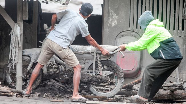 Warga mengevakuasi kendaraannya yang tertimbun material guguran awan panas Gunung Semeru di Desa Sumber Wuluh, Lumajang, Jawa Timur, Senin (6/12/2021).  ANTARA FOTO/Umarul Faruq