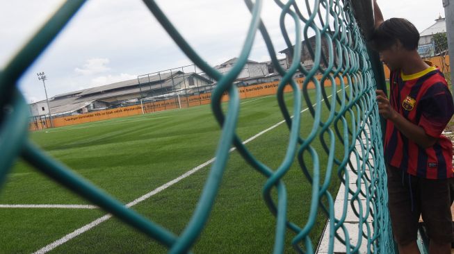 Seorang anak melihat Lapangan Sepakbola Muara Angke yang telah dibangun di Jakarta Utara, Minggu (5/12/2021).  ANTARA FOTO/Indrianto Eko Suwarso