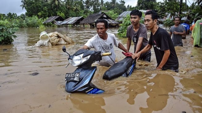 Sejumlah warga mendorong sepeda motornya melewati banjir di Dusun Kebon Lauk, Desa Sesela, Kecamatan Gunungsari, Lombok Barat, NTB, Senin (6/12/2021). Banjir yang terjadi karena hujan lebat dan luapan air Sungai Meninting di wilayah Gunungsari tersebut mengakibatkan ratusan rumah warga terendam. ANTARA FOTO/Ahmad Subaidi/wsj