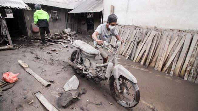 Warga mengevakuasi kendaraannya yang tertimbun material guguran awan panas Gunung Semeru di Desa Sumber Wuluh, Lumajang, Jawa Timur, Senin (6/12/2021) [ANTARA FOTO/Umarul Faruq].