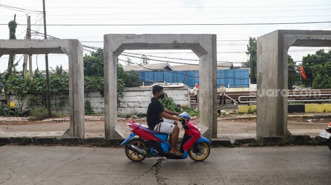 Kendaraan melintas di depan box culvert pembangunan saluran air di Jalan I Gusti Ngurah Rai, Duren Sawit, Jakarta Timur, Selasa (7/12/2021). [Suara.com/Alfian Winanto]