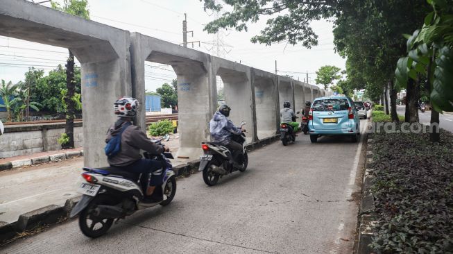 Kendaraan melintas di jalur pembangunan saluran air di Jalan I Gusti Ngurah Rai, Duren Sawit, Jakarta Timur, Selasa (7/12/2021). [Suara.com/Alfian Winanto]