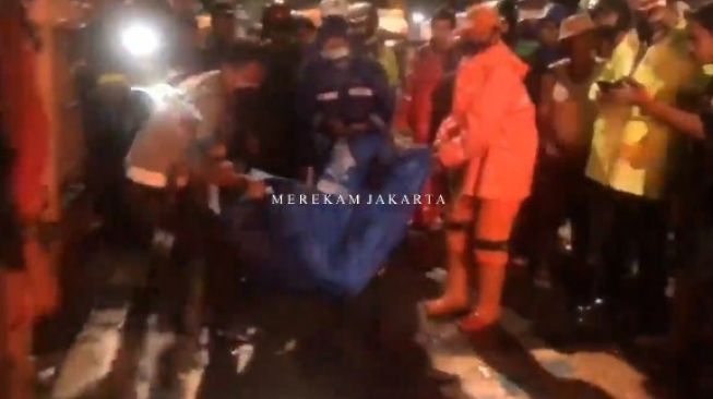 Petugas mengevakuasi jenazah pejalan kaki berinisial RH yang tewas ditabrak bus TransJakarta di Jalan Raya Taman Marga Satwa Raya Gotong, Pasar Minggu, Jakarta Selatan, Senin (6/12/2021) malam. [Tangkapan layar video Instagram @merekamjakarta]