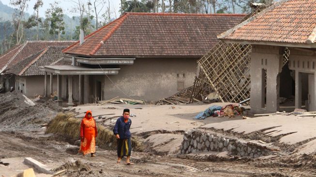 Warga melitas di dekat rumah yang tertimbun material vulkanik gunung Semeru di dusun Umbulan, Pronojiwo, Lumajang, Jawa Timur, Rabu (8/12/2021). ANTARA FOTO/Ari Bowo Sucipto