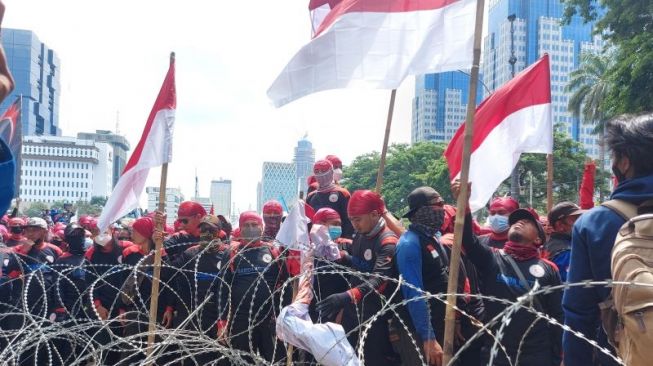 Ribuan buruh dari berbagai federasi mencoba menerobos barikade kawat berduri di Jalan Merdeka Barat, Jakarta Pusat, Rabu (8/7/2021). (ANTARA/Mentari Dwi Gayati)