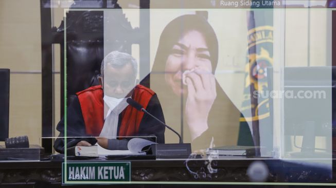 Foto double eksposure Artis Cynthiara Alona menangis ketika mendengar putusan majelis hakim saat menjalani sidang kasus prostitusi anak yang digelar secara virtual di Pengadilan Negeri Tangerang, Banten, Rabu (8/12/2021). [Suara.com/Alfian Winanto]