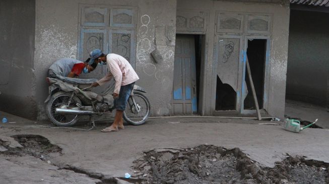 Warga memeriksa motor miliknya yang terkena material vulkanik gunung Semeru di dusun Umbulan, Pronojiwo, Lumajang, Jawa Timur, Rabu (8/12/2021). ANTARA FOTO/Ari Bowo Sucipto