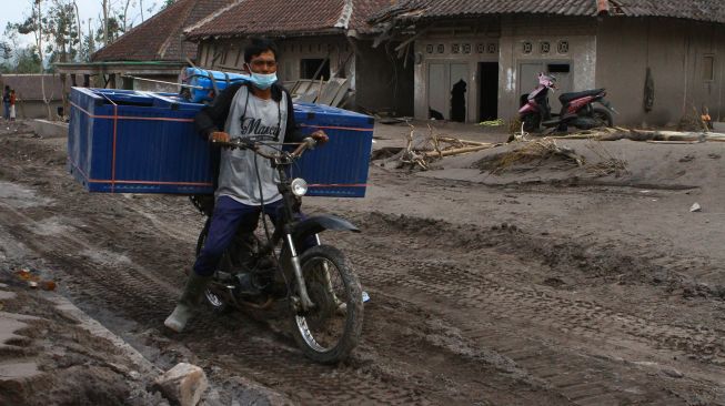 Warga melitas di dekat rumah yang tertimbun material vulkanik gunung Semeru di dusun Umbulan, Pronojiwo, Lumajang, Jawa Timur, Rabu (8/12/2021). ANTARA FOTO/Ari Bowo Sucipto