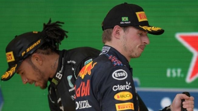 Pembalap Mercedes Lewis Hamilton (kiri) and pembalap Red Bull Max Verstappen (kanan) di podium setelah setelah masing-masing meraih posisi pertama dan kedua di F1 GP Brasil di Interlagos, Sao Paulo, pada 14 November 2021. CARL DE SOUZA / AFP