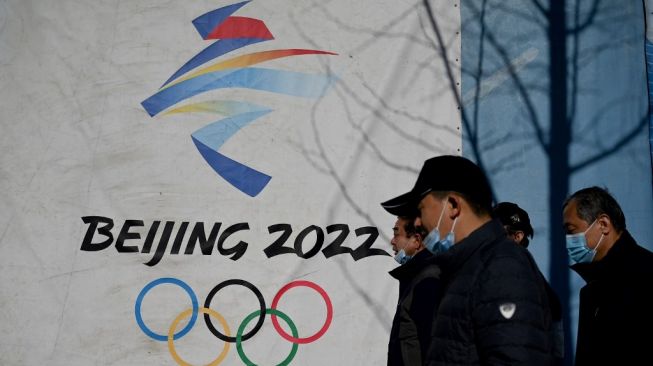 Arsip - Dalam file foto yang diambil pada 1 Desember 2021, orang-orang berjalan melewati logo Olimpiade Musim Dingin Beijing 2022 di Taman Shougang di Beijing.Noel Celis / AFP.