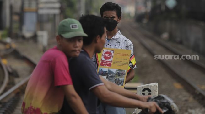 Relawan dari komunitas Railfans melakukan sosialisasi keselamatan di perlintasan sebidang Bukit Duri, Jakarta, Sabtu (11/12/2021). [Suara.com/Angga Budhiyanto]