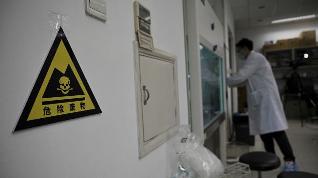 Seorang teknisi laboratorium bekerja di laboratorium Universitas Tsinghua, Beijing, China, pada (9/12/2021). [NOEL CELIS / AFP]