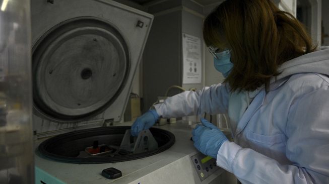 Seorang teknisi laboratorium bekerja di laboratorium Universitas Tsinghua, Beijing, China, pada (9/12/2021). [NOEL CELIS / AFP]