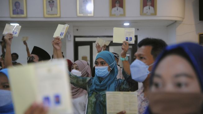 Sejumlah pasangan suami istri menunjukkan buku nikah saat Itsbat Nikah Massal di ruangan Paseban Sri Baduga, Balaikota Bogor, Jawa Barat, Sabtu (11/12/2021). [ANTARA FOTO/Arif Firmansyah]