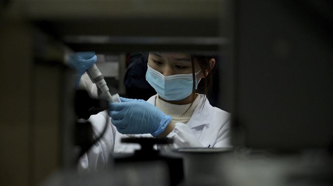 Seorang teknisi laboratorium bekerja di laboratorium Universitas Tsinghua, Beijing, China, pada (9/12/2021). [NOEL CELIS / AFP]