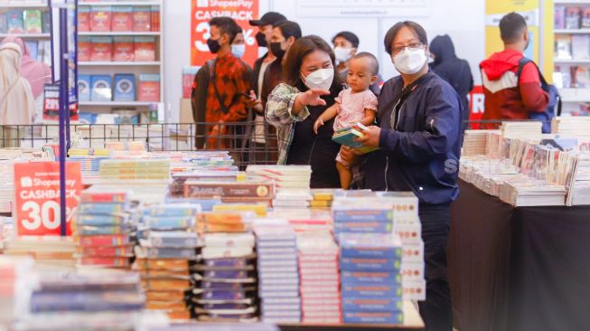 Pengunjung memilih buku dalam pameran Indonesia Internationa Book Fair (IIBF) 2021 di JCC Senayan, Jakarta Pusat, Minggu (12/12/2021). [Suara.com/Alfian Winanto]