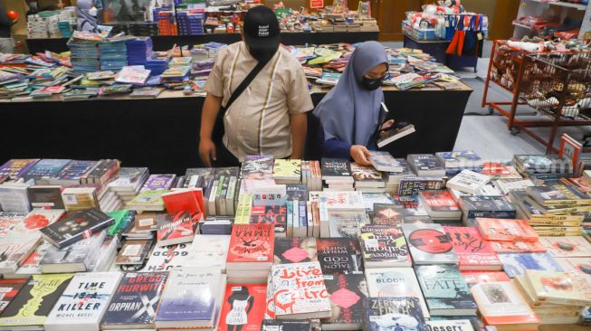 Pengunjung memilih buku dalam pameran Indonesia Internationa Book Fair (IIBF) 2021 di JCC Senayan, Jakarta Pusat, Minggu (12/12/2021). [Suara.com/Alfian Winanto]