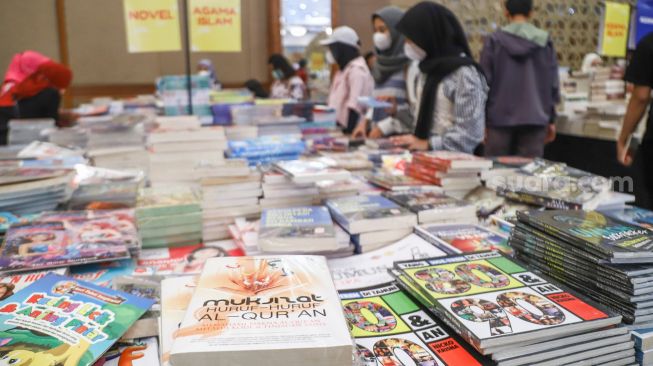 Pengunjung memilih buku dalam pameran Indonesia Internationa Book Fair (IIBF) 2021 di JCC Senayan, Jakarta Pusat, Minggu (12/12/2021). [Suara.com/Alfian Winanto]