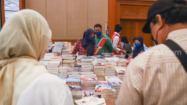 Pengunjung memilih buku dalam pameran Indonesia Internationa Book Fair (IIBF) 2021 di JCC Senayan, Jakarta Pusat, Minggu (12/12/2021). [Suara.com/Alfian Winanto]