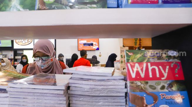 Pengunjung memilih buku dalam pameran Indonesia Internationa Book Fair (IIBF) 2021 di JCC Senayan, Jakarta Pusat, Minggu (12/12/2021). [Suara.com/Alfian Winanto]