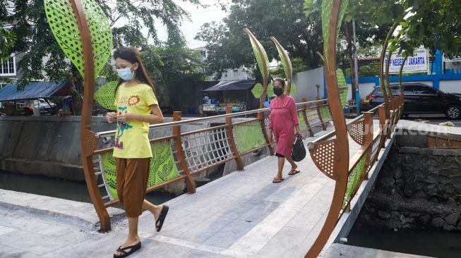 Warga melintasi jembatan di Jalan Galur Sari Timur, Matraman, Jakarta Timur, Senin (13/12/2021). [Suara.com/Alfian Winanto]