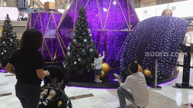 Pengunjung melihat dekorasi perayaan Natal bertema "A Shining Shimmering Christmas" di Mal Grand Indonesia, Jakarta, Senin (13/12/2021). [Suara.com/Angga Budhiyanto]