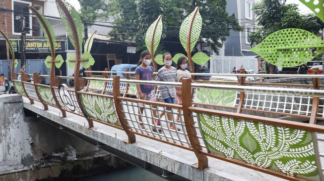 Anak-anak melintasi jembatan di Jalan Galur Sari Timur, Matraman, Jakarta Timur, Senin (13/12/2021). [Suara.com/Alfian Winanto]