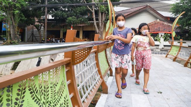 Anak-anak melintasi jembatan di Jalan Galur Sari Timur, Matraman, Jakarta Timur, Senin (13/12/2021). [Suara.com/Alfian Winanto]