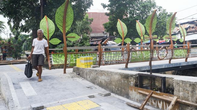 Warga melintasi jembatan di Jalan Galur Sari Timur, Matraman, Jakarta Timur, Senin (13/12/2021). [Suara.com/Alfian Winanto]