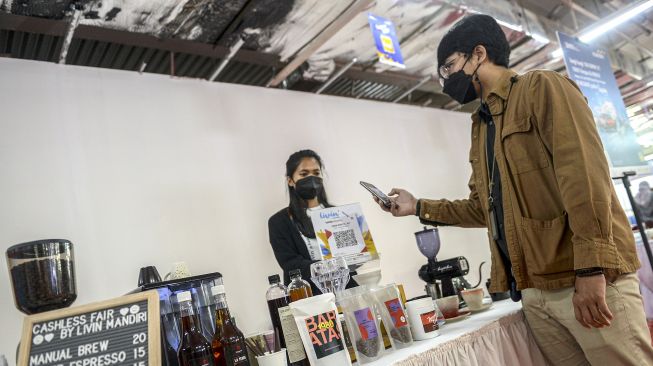 Pembeli memindai kode batang atau QR code Indonesia Standar (QRIS) di kedai kopi pada gelaran Cashless Fair by Livin' di Thamrin City, Jakarta, Selasa (14/12/2021).  ANTARA FOTO/M Risyal Hidayat