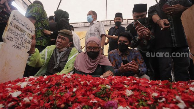 Keluarga dan kerabat berdoa di pusara almarhum politikus senior Abraham Lunggana atau Haji Lulung di TPU Karet Bivak, Jakarta, Selasa (14/12/2021). [Suara.com/Angga Budhiyanto]