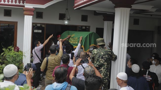 Keluarga dan kerabat mengusung peti jenazah almarhum politikus senior Abraham Lunggana atau Haji Lulung setibanya di rumah duka di kawasan Sukabumi Utara, Kebon Jeruk, Jakarta, Selasa (14/12/2021). [Suara.com/Angga Budhiyanto]