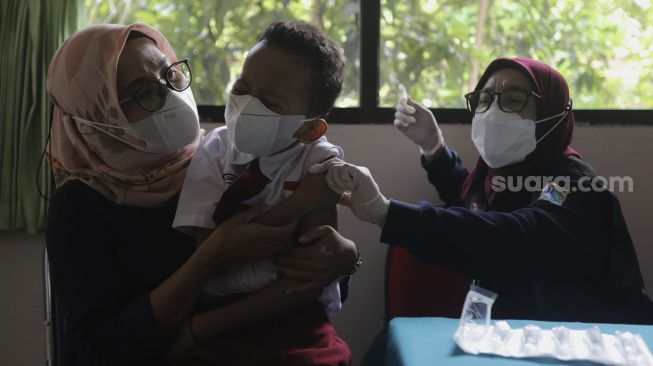 Orang tua menenangkan anaknya yang akan mendapatkan vaksin COVID-19 kepada pelajar di SDN 04 Cilandak Barat, Jakarta, Selasa (14/12/2021). [Suara.com/Angga Budhiyanto]