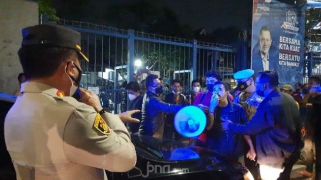 Sejumlah mahasiswa pendemo ketika bernegosiasi dengan Kapolsek Menteng AKBP Iver Son Manossoh di depan Kantor DPP Partai Demokrat pada Senin (15/3/2021) malam. (JPNN.com/Kenny Kurnia Putra)