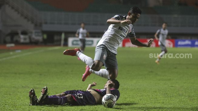 Pemain belakang RANS Cilegon FC Hamka Hamzah melepaskan tekel terhadap penyerang Persis Solo Miftahul Hamdi selama pertandingan grup X babak 8 besar Liga 2 antara RANS Cilegon FC melawan Persis Solo di Stadion Pakansari, Bogor, Jawa Barat, Rabu (15/12/2021). [Suara.com/Angga Budhiyanto]