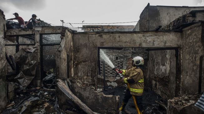 Personel Damkar melakukan pendinginan pascakebakaran di permukiman padat penduduk Kramat Pulo, Senen, Jakarta, Rabu (15/12/2021).  ANTARA FOTO/Aprillio Akbar