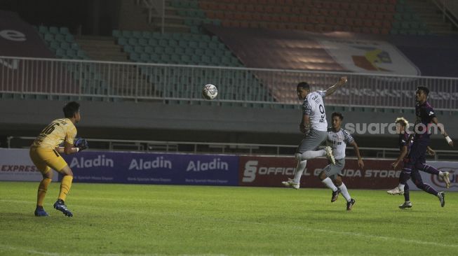 Penyerang Persis Solo Alberto Goncalves berusaha mencetak gol melalui sundulan selama pertandingan grup X babak 8 besar Liga 2 antara RANS Cilegon FC melawan Persis Solo di Stadion Pakansari, Bogor, Jawa Barat, Rabu (15/12/2021). [Suara.com/Angga Budhiyanto]