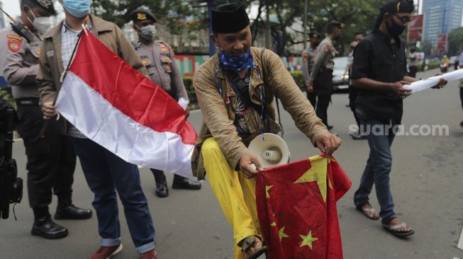 Massa yang tergabung dalam Forum Cinta Tanah Air membawa bendera China saat melakukan aksi unjuk rasa di depan Kedubes Republik Rakyat China (RRC), Jakarta, Rabu (15/12/2021). [Suara.com/Angga Budhiyanto]