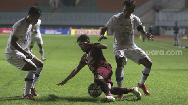 Gelandang Sriwijaya FC Hari Habrian (tengah) dilanggar oleh gelandang Persiba Balikpapan Bryan Caesar (kanan) selama pertandingan grup X babak 8 besar Liga 2 antara Sriwijaya FC melawan Persiba Balikpapan di Stadion Pakansari, Bogor, Jawa Barat, Rabu (15/12/2021). [Suara.com/Angga Budhiyanto]