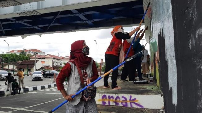  Sejumlah Pekerja Rumah Tangga (PRT) mengecat tembok untuk membuat mural sebagai aksi segera Disahkannya RUU Perlindungan PRT di Jembatan Kewek, Kota Jogja, Rabu (15/12/2021). [Muhammad Ilham Baktora / SuaraJogja.id]