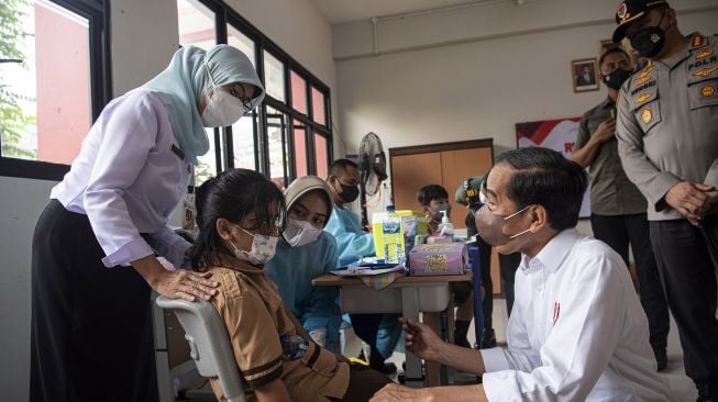 Presiden Joko Widodo (kanan) berdialog dengan sejumlah anak yang menunggu observasi setelah vaksinasi COVID-19 di Kompleks SDN Cideng, Gambir, Jakarta Pusat, Rabu (15/12/2021).  ANTARA FOTO/Sigid Kurniawan
