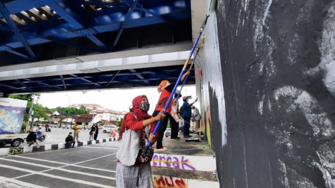  Sejumlah Pekerja Rumah Tangga (PRT) mengecat tembok untuk membuat mural sebagai aksi segera Disahkannya RUU Perlindungan PRT di Jembatan Kewek, Kota Jogja, Rabu (15/12/2021). [Muhammad Ilham Baktora / SuaraJogja.id]